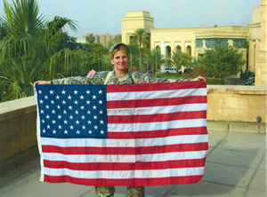CW5 Geri Bowers holding up flag that was flown specificially for Tom Stevens